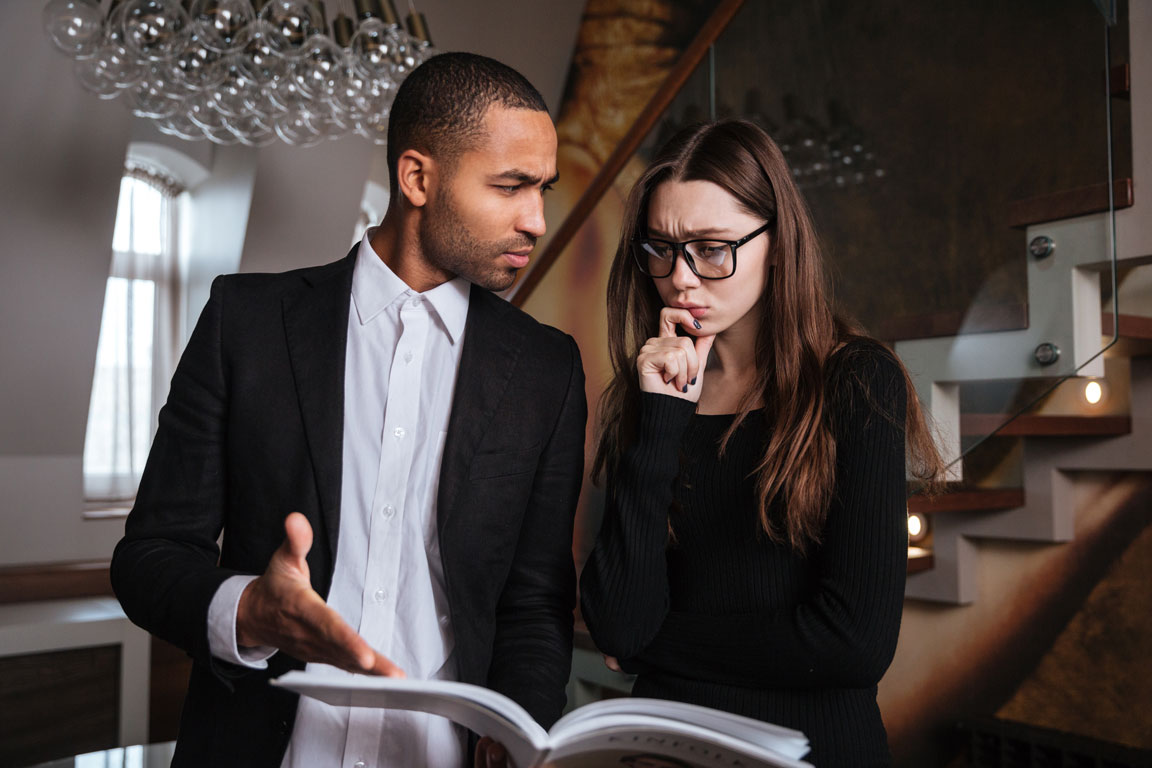 graphicstock-serious-african-man-in-suit-talking-with-woman-in-glasses-and-pointing-at-journal_SObcyVaU2x